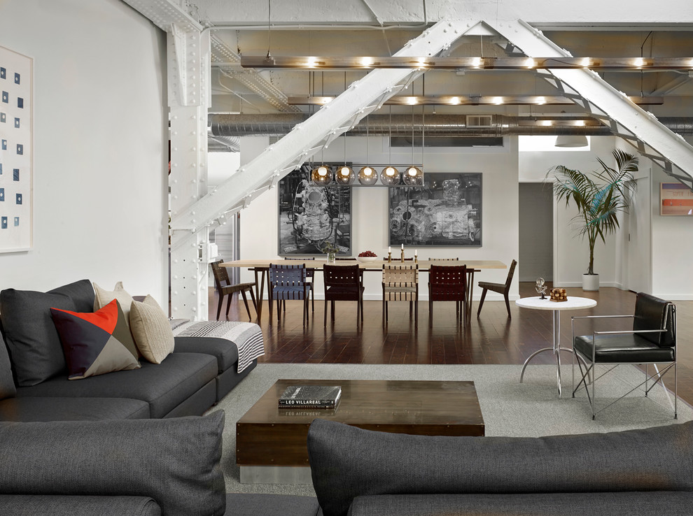 Immagine di un ampio soggiorno industriale aperto con pavimento in legno massello medio e pareti bianche