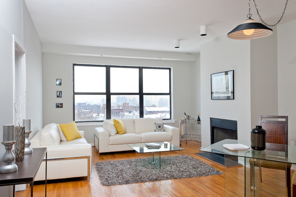 Offenes Modernes Wohnzimmer mit grauer Wandfarbe, hellem Holzboden und Kamin in New York