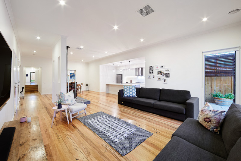 Mittelgroßes, Abgetrenntes Maritimes Wohnzimmer mit weißer Wandfarbe, hellem Holzboden, Kamin, Kaminumrandung aus Metall und TV-Wand in Melbourne