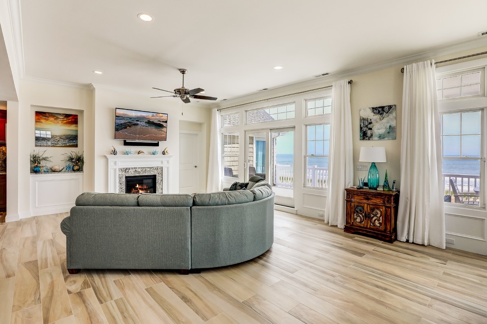 Large beach style open plan living room in New York with beige walls, porcelain flooring, a standard fireplace, a tiled fireplace surround and beige floors.