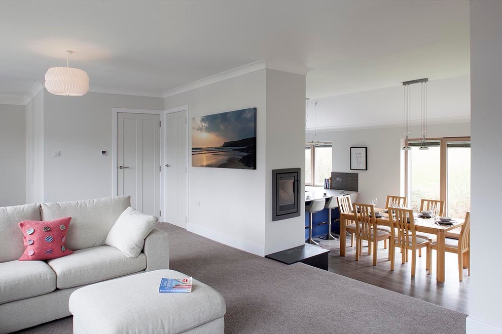 Großes, Offenes Modernes Wohnzimmer mit weißer Wandfarbe, Teppichboden, Eckkamin, Kaminumrandung aus Metall und verstecktem TV in Cornwall