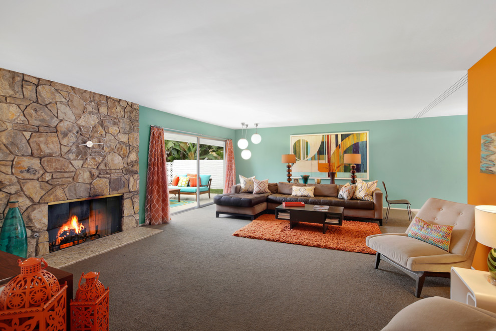 オレンジカウンティにあるミッドセンチュリースタイルのおしゃれなLDK (青い壁、カーペット敷き、標準型暖炉、石材の暖炉まわり、グレーの床) の写真