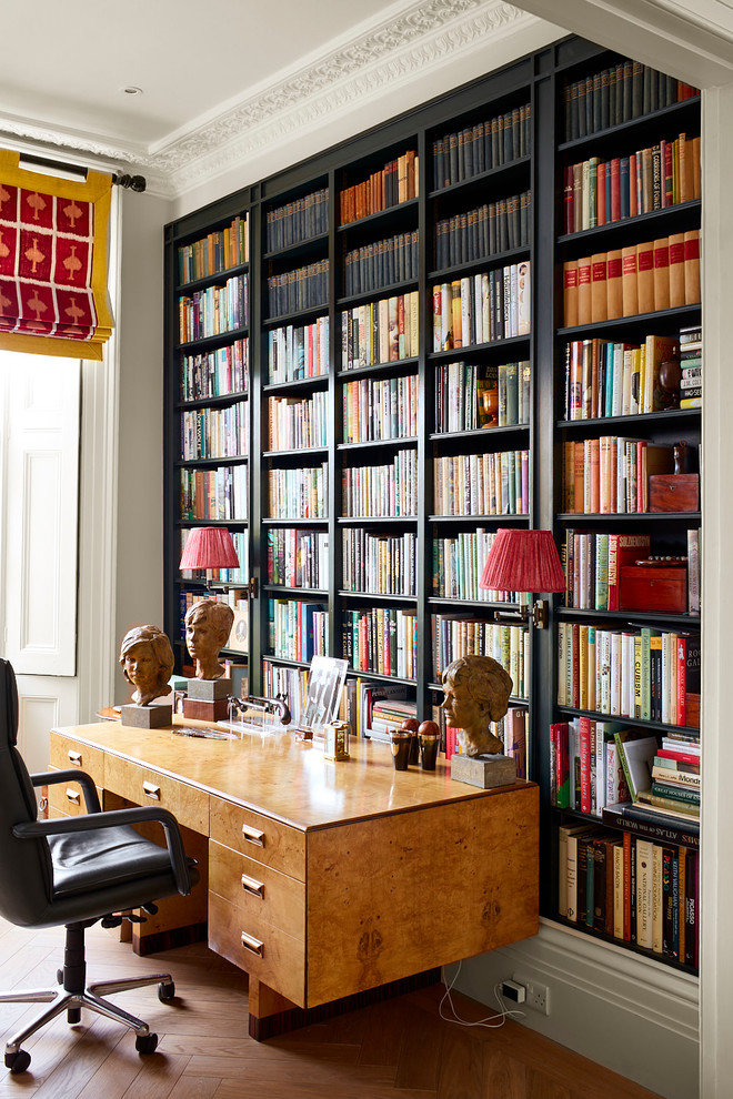 Modernes Arbeitszimmer mit Arbeitsplatz, beiger Wandfarbe, braunem Holzboden, freistehendem Schreibtisch und braunem Boden in London