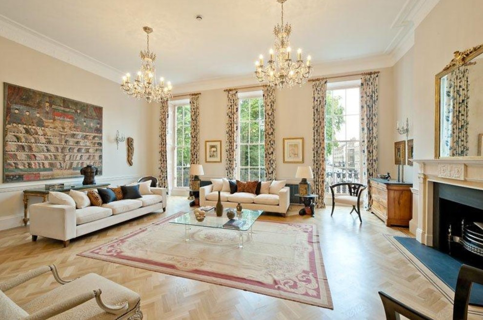 Expansive traditional living room in London with beige walls, light hardwood flooring, a standard fireplace, a metal fireplace surround, no tv and beige floors.