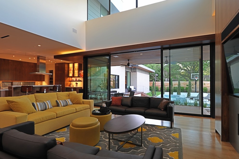 Modernes Wohnzimmer mit braunem Holzboden, Tunnelkamin, Kaminumrandung aus Holz und Multimediawand in Houston