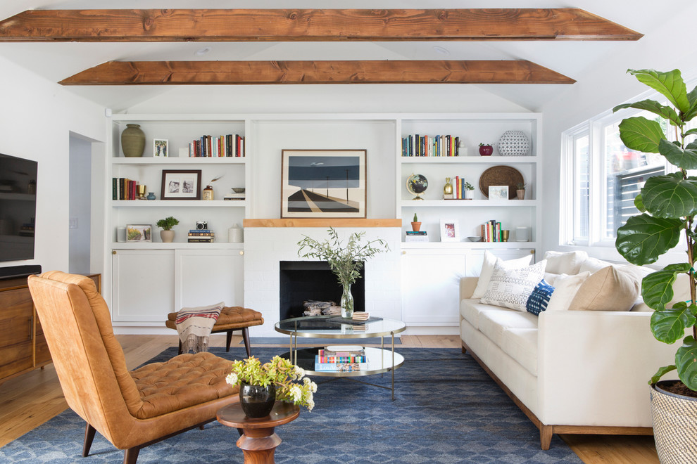 Klassisches Wohnzimmer mit weißer Wandfarbe, braunem Holzboden, Kamin, Kaminumrandung aus Backstein, TV-Wand und braunem Boden in Los Angeles