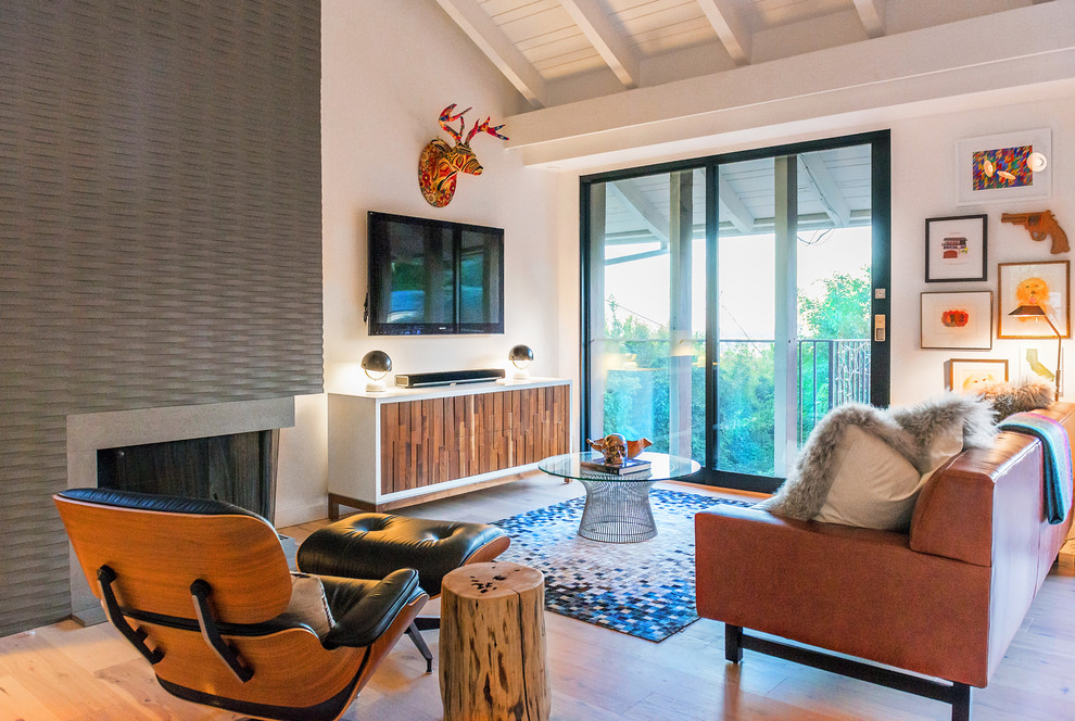 Kleines Eklektisches Wohnzimmer im Loft-Stil mit bunten Wänden, hellem Holzboden, Eckkamin, verputzter Kaminumrandung und TV-Wand in Los Angeles