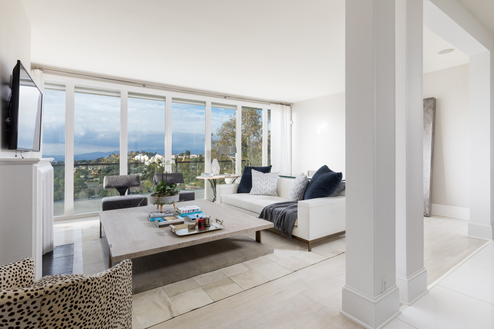 Immagine di un grande soggiorno design aperto con camino classico, cornice del camino in intonaco, pareti bianche e parquet chiaro