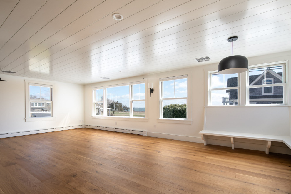 Imagen de salón abierto costero pequeño sin chimenea y televisor con paredes blancas, suelo de madera en tonos medios, suelo marrón y machihembrado