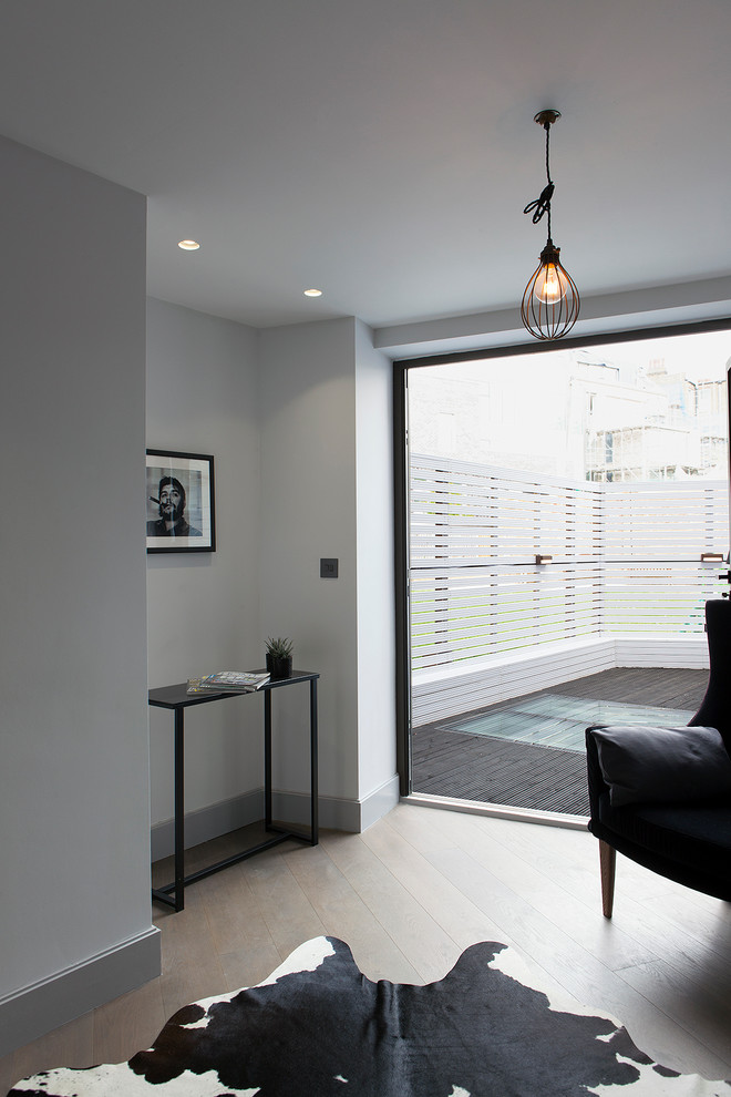 Источник вдохновения для домашнего уюта: маленькая открытая гостиная комната в современном стиле с серыми стенами, деревянным полом, телевизором на стене и серым полом для на участке и в саду