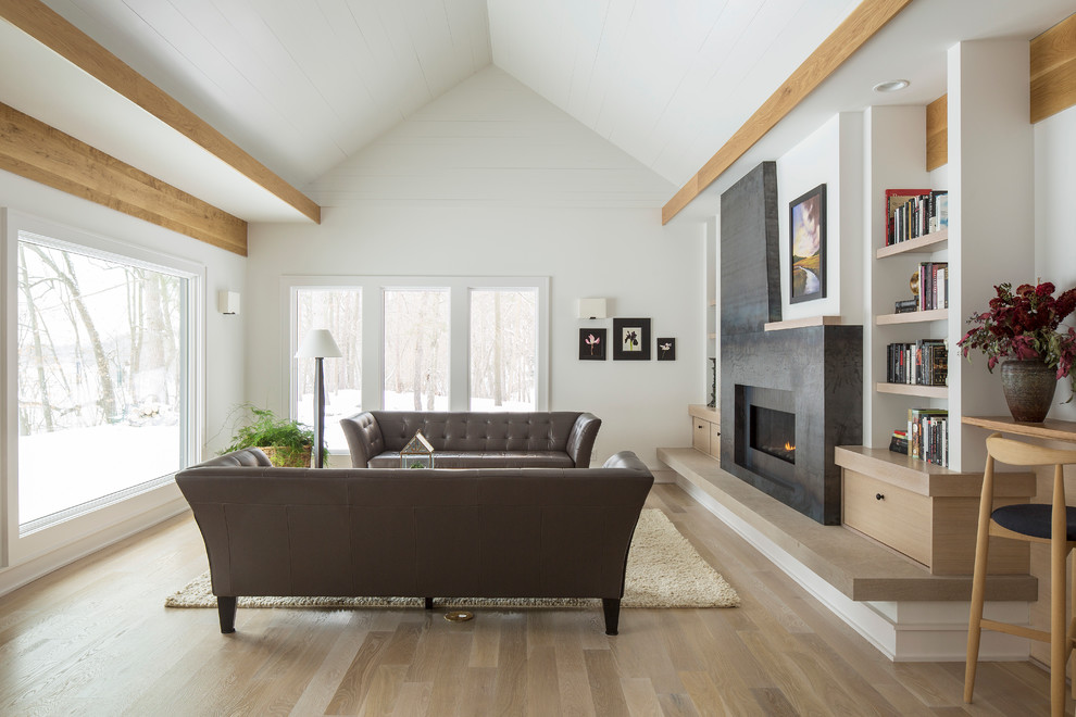 Modelo de salón minimalista con paredes blancas, suelo de madera en tonos medios, chimenea lineal y marco de chimenea de piedra