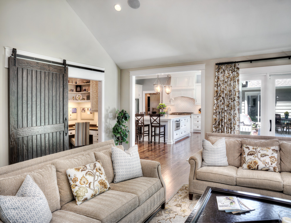 Immagine di un ampio soggiorno tradizionale aperto con pareti beige e pavimento in legno massello medio