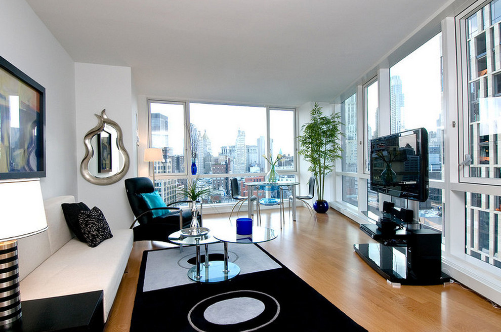 Foto de salón actual con paredes blancas, suelo de madera clara y televisor independiente