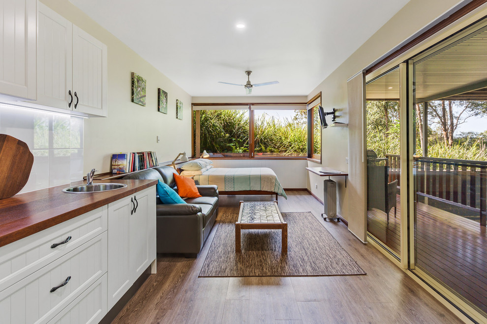 Immagine di un soggiorno tropicale con pareti beige, pavimento in legno massello medio e pavimento marrone