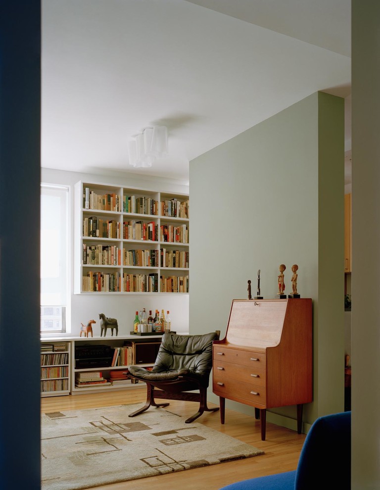 Immagine di un piccolo soggiorno design chiuso con libreria, pareti bianche, pavimento in legno massello medio, nessun camino, TV a parete e pavimento marrone