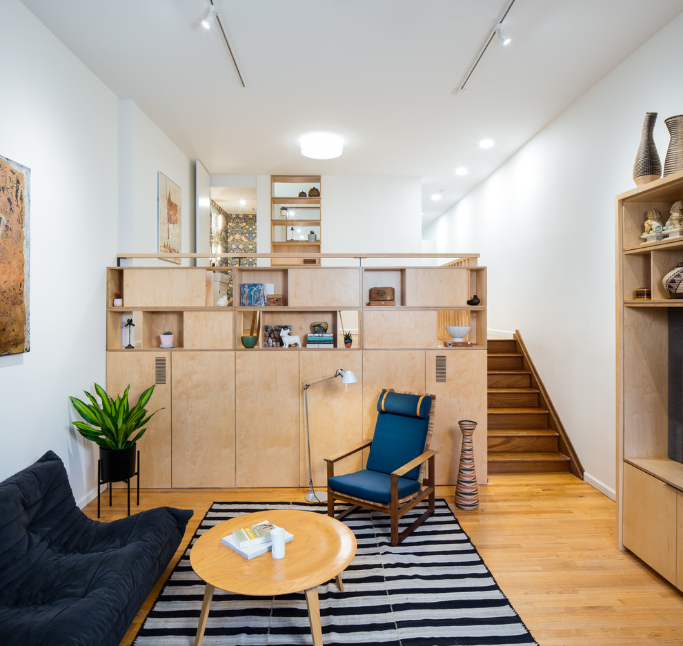Diseño de salón abierto escandinavo de tamaño medio con paredes blancas, pared multimedia, suelo de madera en tonos medios y suelo marrón