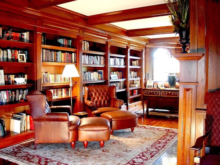 Esempio di un grande soggiorno classico chiuso con libreria, pavimento in legno massello medio, camino classico e cornice del camino in legno