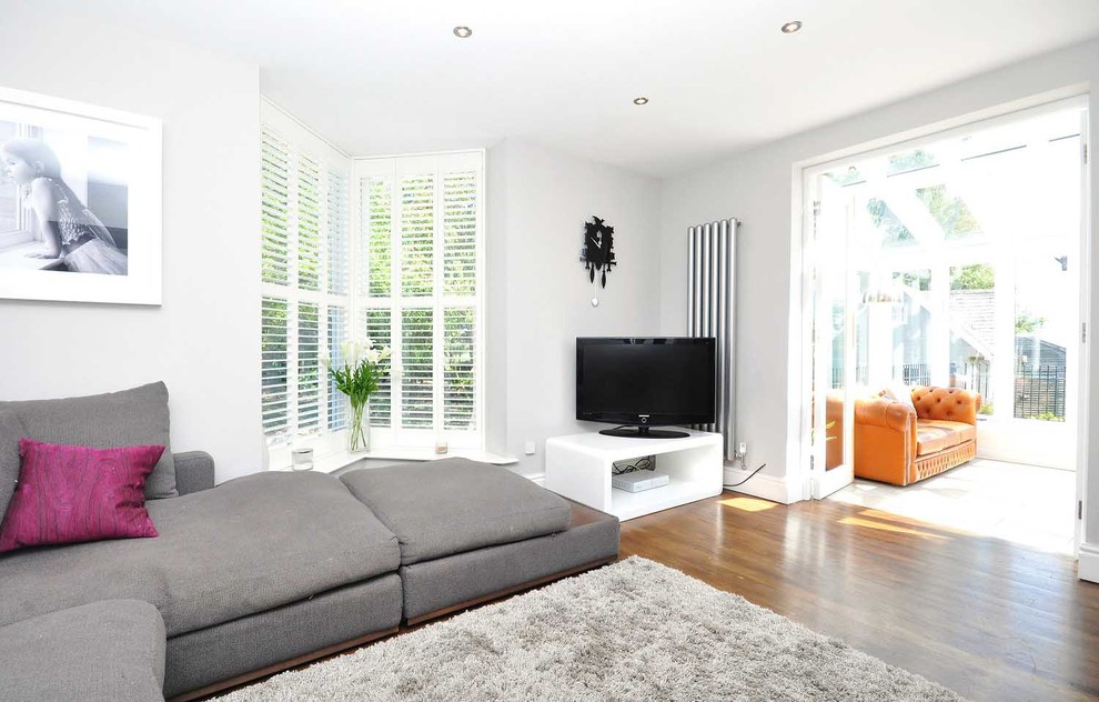 На фото: гостиная комната в современном стиле с серыми стенами и отдельно стоящим телевизором с