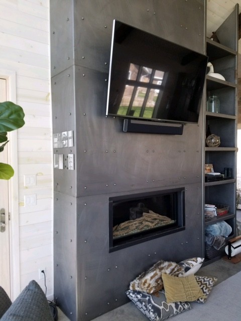 他の地域にある中くらいなインダストリアルスタイルのおしゃれなLDK (白い壁、コンクリートの床、横長型暖炉、金属の暖炉まわり、壁掛け型テレビ、グレーの床) の写真