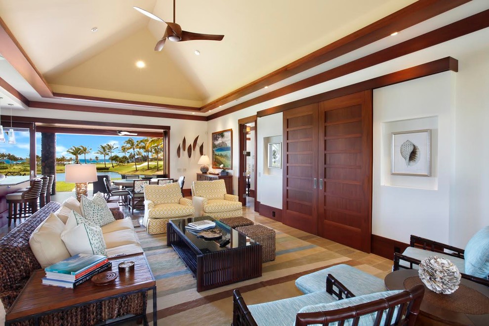 Example of a large island style open concept limestone floor and beige floor living room design in Hawaii with white walls, no fireplace and a wall-mounted tv