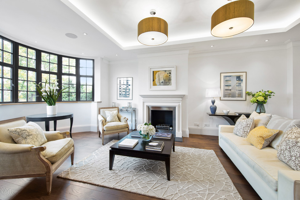 Mittelgroßes, Abgetrenntes Klassisches Wohnzimmer mit weißer Wandfarbe, dunklem Holzboden, Kamin, Kaminumrandung aus Stein und braunem Boden in London