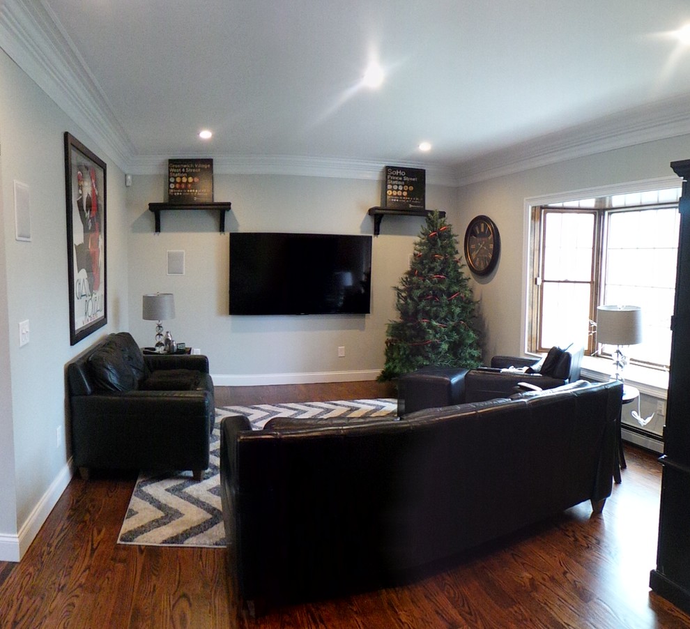 Exempel på ett mellanstort klassiskt allrum med öppen planlösning, med grå väggar, mellanmörkt trägolv, en öppen vedspis, en spiselkrans i sten och en väggmonterad TV