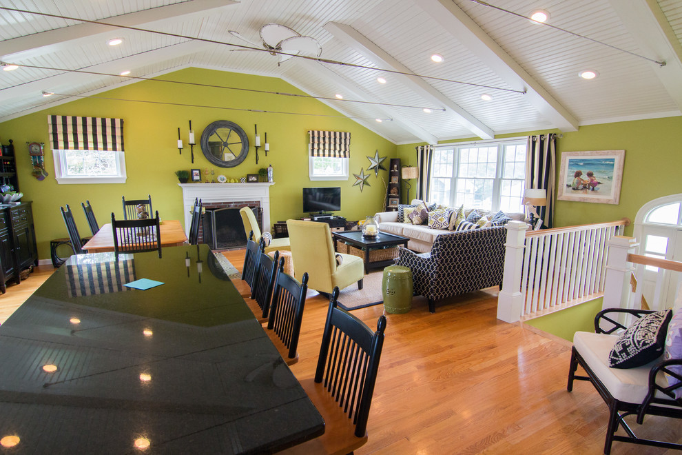 Пример оригинального дизайна: открытая гостиная комната в морском стиле с зелеными стенами, паркетным полом среднего тона, стандартным камином, фасадом камина из кирпича и отдельно стоящим телевизором