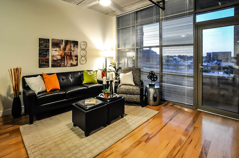 Small industrial open plan living room in Chicago with beige walls and light hardwood flooring.