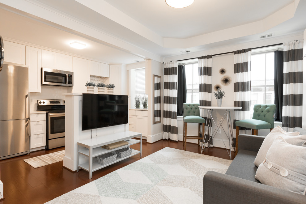 На фото: гостиная комната в стиле неоклассика (современная классика) с белыми стенами, темным паркетным полом и телевизором на стене с