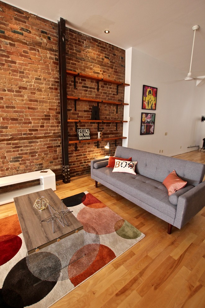 Large industrial open plan living room in Montreal with red walls, light hardwood flooring and no fireplace.