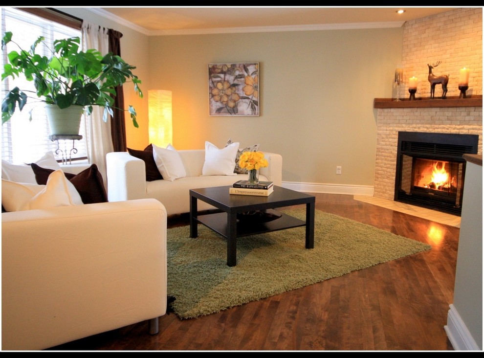 Immagine di un piccolo soggiorno minimal aperto con pareti verdi, pavimento in legno massello medio, camino classico e cornice del camino in mattoni