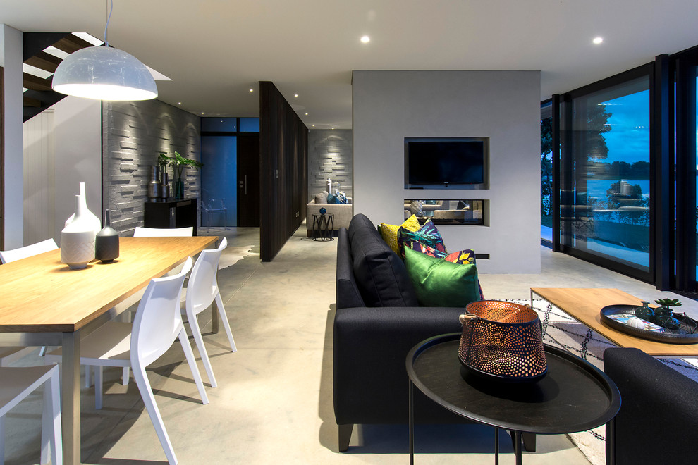 Стильный дизайн: гостиная комната в современном стиле с двусторонним камином, фасадом камина из штукатурки и телевизором на стене - последний тренд