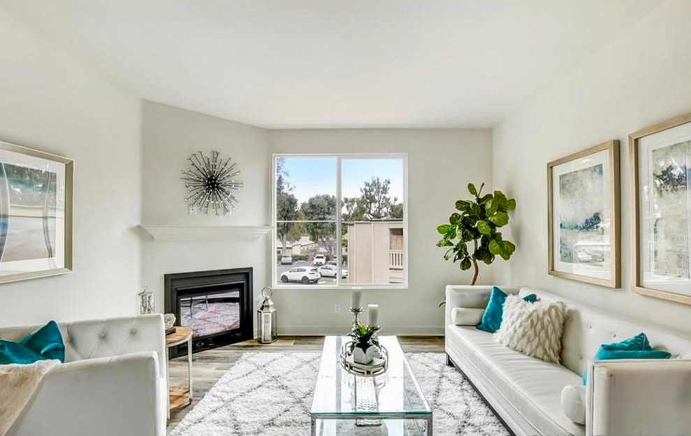 サンディエゴにある高級な中くらいなトランジショナルスタイルのおしゃれなリビング (白い壁、無垢フローリング、コーナー設置型暖炉、漆喰の暖炉まわり、壁掛け型テレビ、グレーの床) の写真