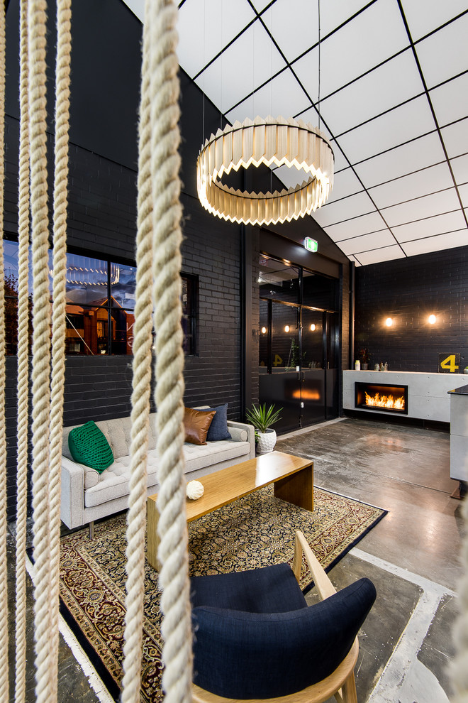 Свежая идея для дизайна: открытая гостиная комната среднего размера в стиле лофт с черными стенами, бетонным полом, стандартным камином и фасадом камина из бетона - отличное фото интерьера