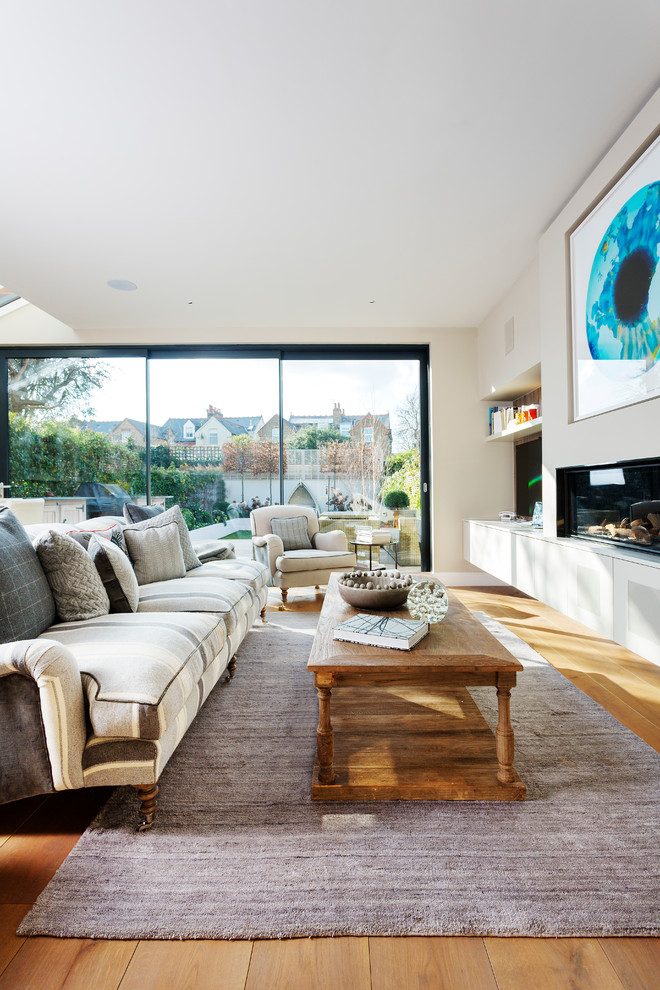 Immagine di un grande soggiorno chic aperto con pareti beige e pavimento in legno massello medio