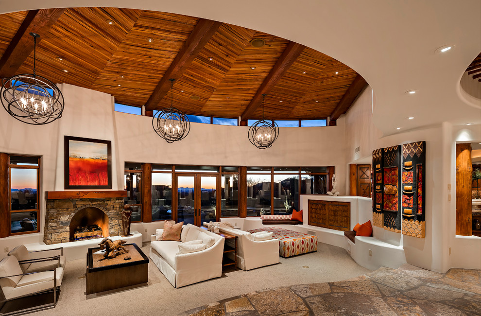 フェニックスにあるサンタフェスタイルのおしゃれなLDK (白い壁、カーペット敷き、標準型暖炉、石材の暖炉まわり、ベージュの床) の写真