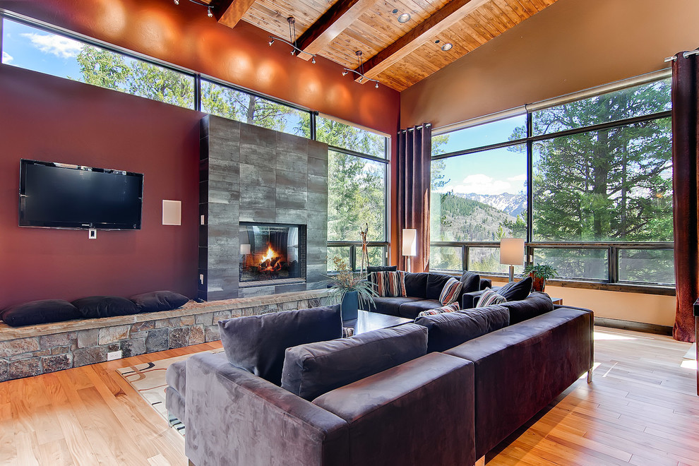 Foto di un soggiorno design con pareti rosse, pavimento in legno massello medio, camino classico e TV a parete