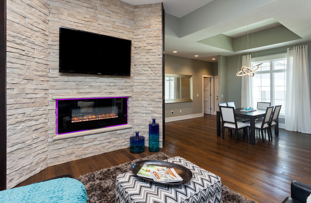 Пример оригинального дизайна: гостиная комната в стиле модернизм с серыми стенами, паркетным полом среднего тона, горизонтальным камином, фасадом камина из камня и телевизором на стене