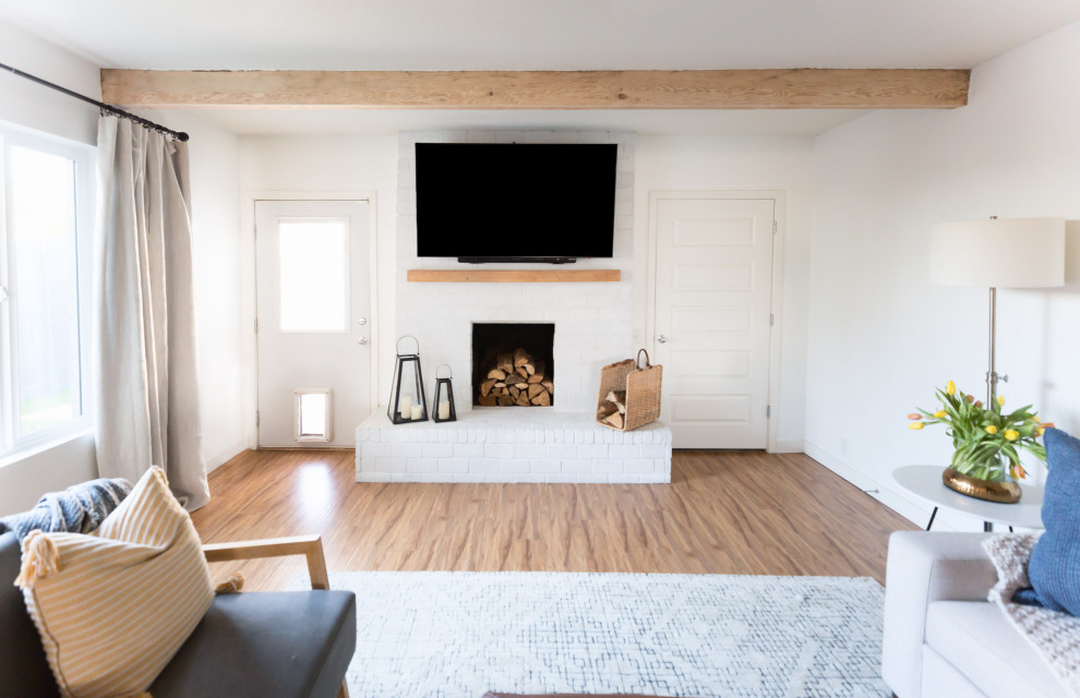 フェニックスにあるお手頃価格の中くらいなカントリー風のおしゃれなLDK (白い壁、ラミネートの床、標準型暖炉、レンガの暖炉まわり、壁掛け型テレビ、ベージュの床) の写真