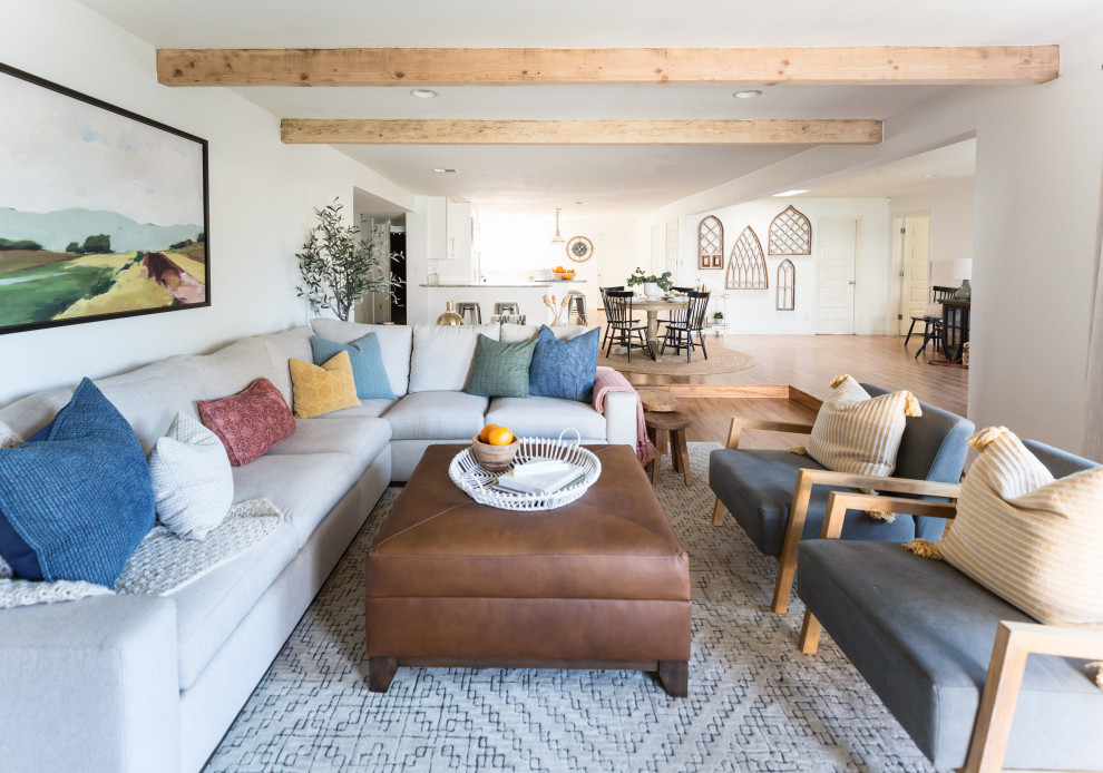 Inspiration for a medium sized farmhouse open plan living room in Phoenix with white walls, laminate floors, a standard fireplace, a brick fireplace surround, a wall mounted tv and beige floors.