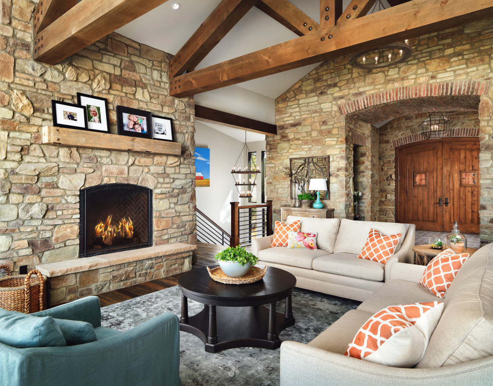Design ideas for a rustic formal open plan living room in Denver with white walls, dark hardwood flooring, a standard fireplace, a stacked stone fireplace surround, no tv, brown floors, exposed beams and a vaulted ceiling.