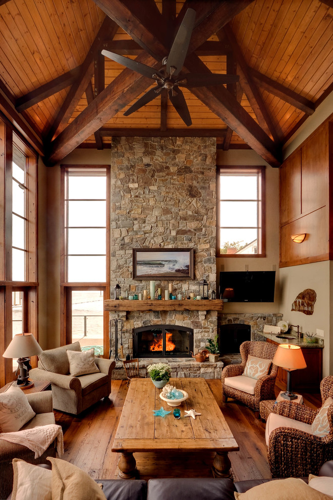 Foto de salón para visitas rústico con paredes beige, suelo de madera en tonos medios, todas las chimeneas, marco de chimenea de piedra y televisor colgado en la pared