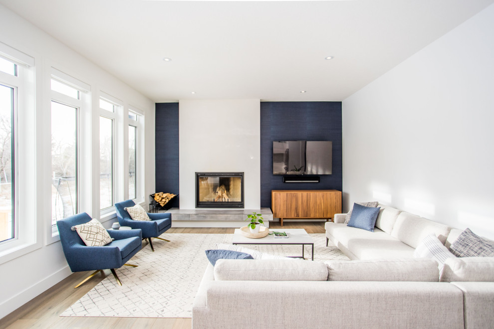 Идея дизайна: изолированная гостиная комната в современном стиле с синими стенами, фасадом камина из штукатурки, телевизором на стене, паркетным полом среднего тона, стандартным камином и коричневым полом