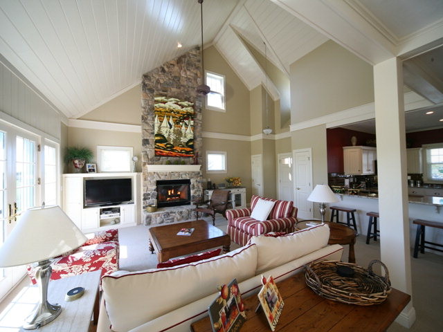 Cette image montre un salon bohème de taille moyenne et ouvert avec un mur vert, un sol en carrelage de céramique, une cheminée standard, un manteau de cheminée en pierre et un téléviseur encastré.
