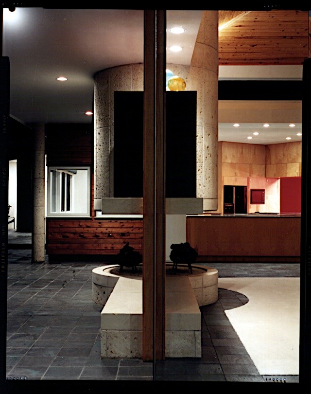 На фото: большая открытая гостиная комната в средиземноморском стиле с белыми стенами, двусторонним камином и фасадом камина из камня