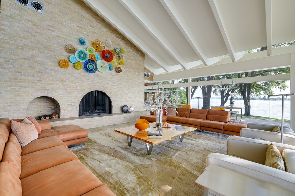 Immagine di un grande soggiorno minimalista aperto con pavimento in ardesia, camino classico e cornice del camino in mattoni