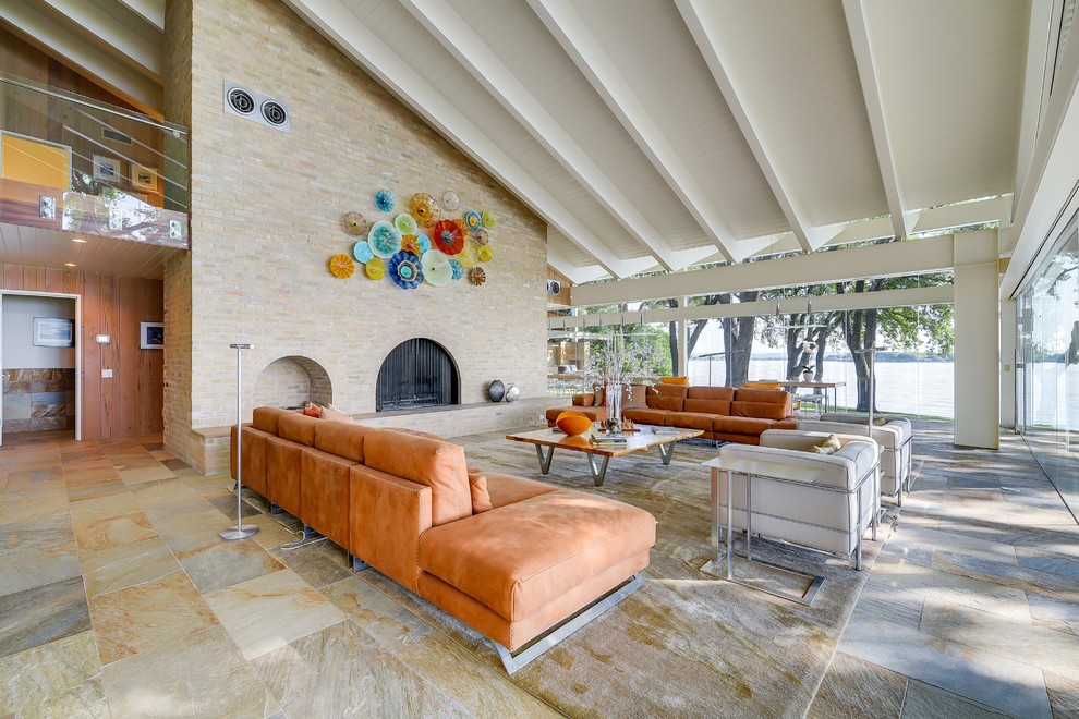 Foto di un grande soggiorno minimalista aperto con pavimento in ardesia, camino classico e cornice del camino in mattoni