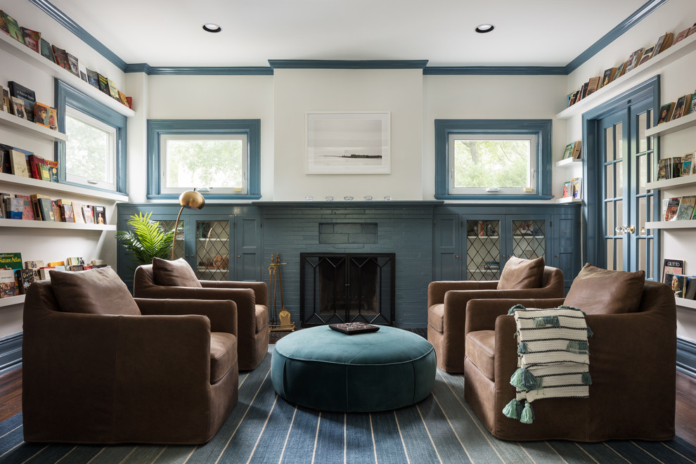 Large beach style enclosed living room in New York with a reading nook, white walls, dark hardwood flooring, a standard fireplace, a brick fireplace surround and brown floors.