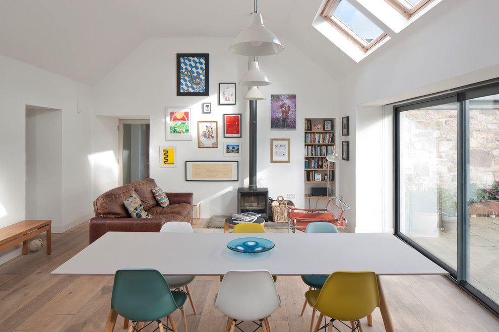 This is an example of a contemporary open plan living room in Other with white walls, light hardwood flooring, a wood burning stove and brown floors.