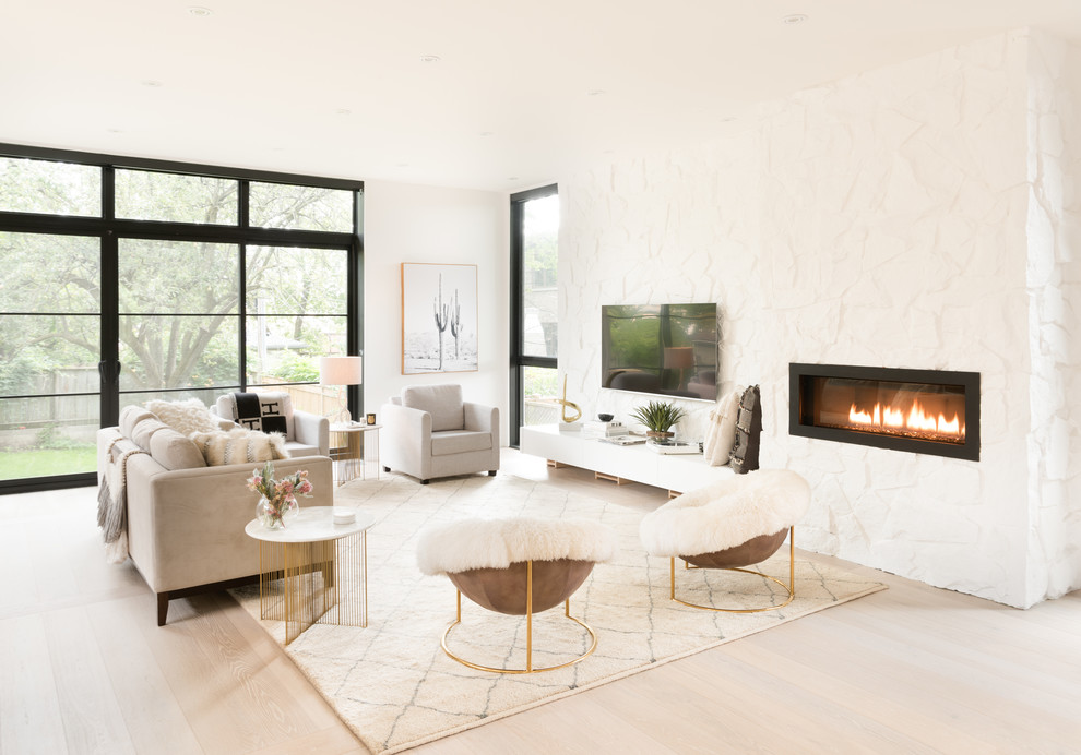 Photo of a scandinavian open plan living room in Toronto with white walls, light hardwood flooring, a ribbon fireplace, a stone fireplace surround, a wall mounted tv and beige floors.